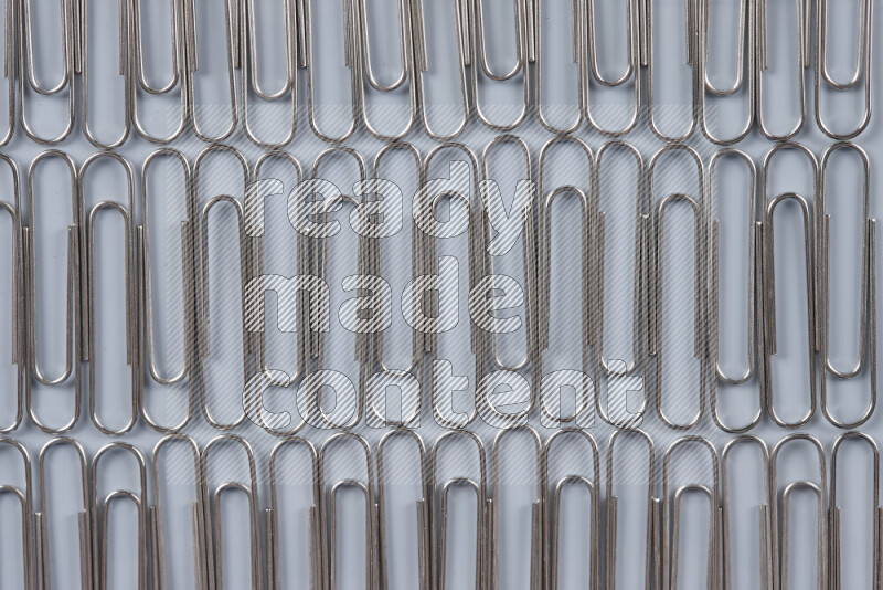 Silver paper clips isolated on a grey background