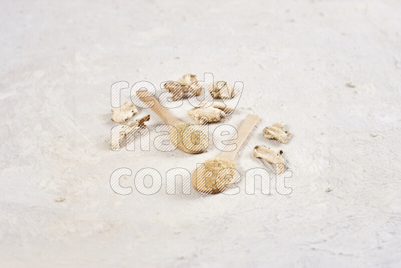 Two wooden spoons full of ground ginger powder on white background