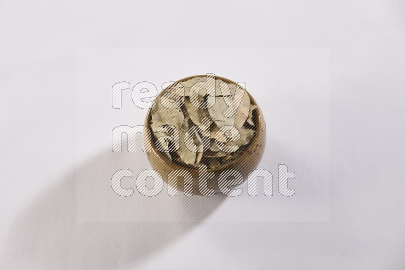 A multicolored pottery bowl full of dried bay leaves on white flooring in different angles