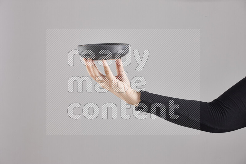 A woman in black abaya holding different pottery essentials in different positions
