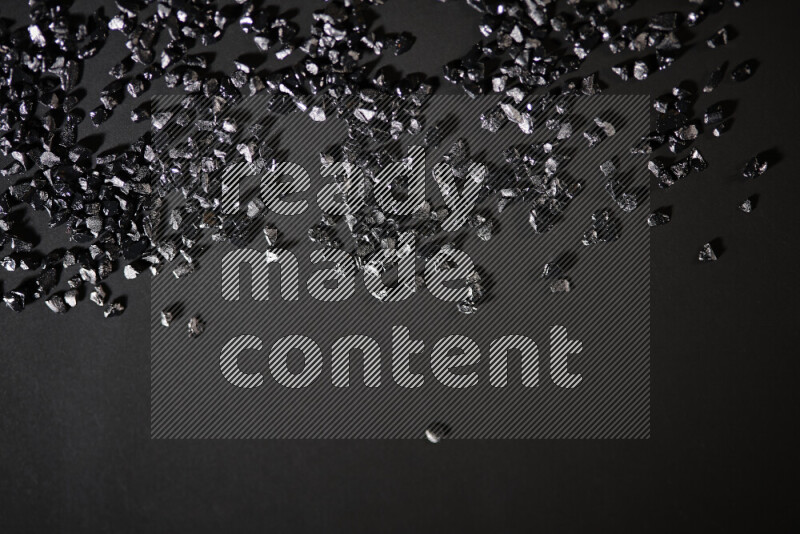 Black shimmering fragments of glass scattered on a black background