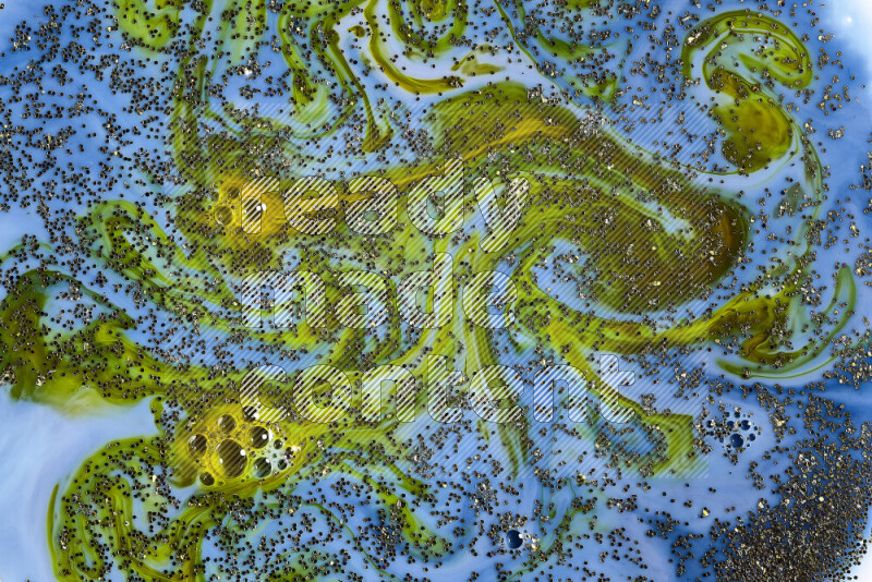 A close-up of sparkling gold glitter scattered on swirling blue and green background