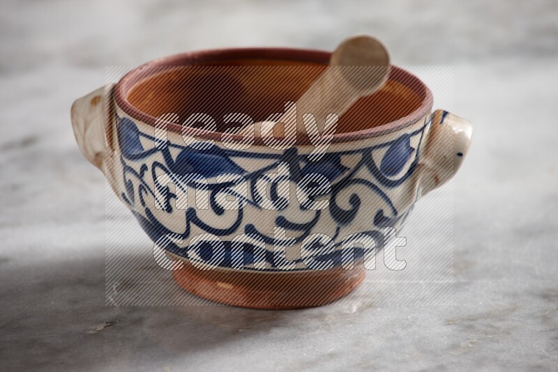 Decorative pottery pot with wooden honey dipper in it on grey marble background