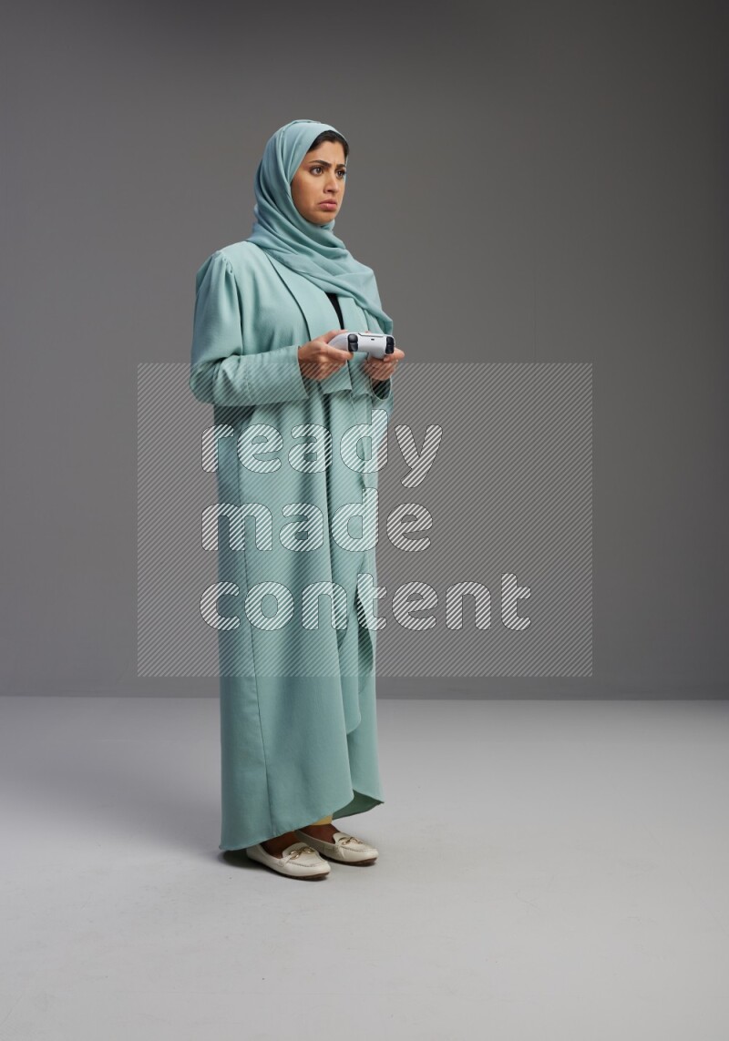 Saudi Woman wearing Abaya standing Playing Games on Gray background