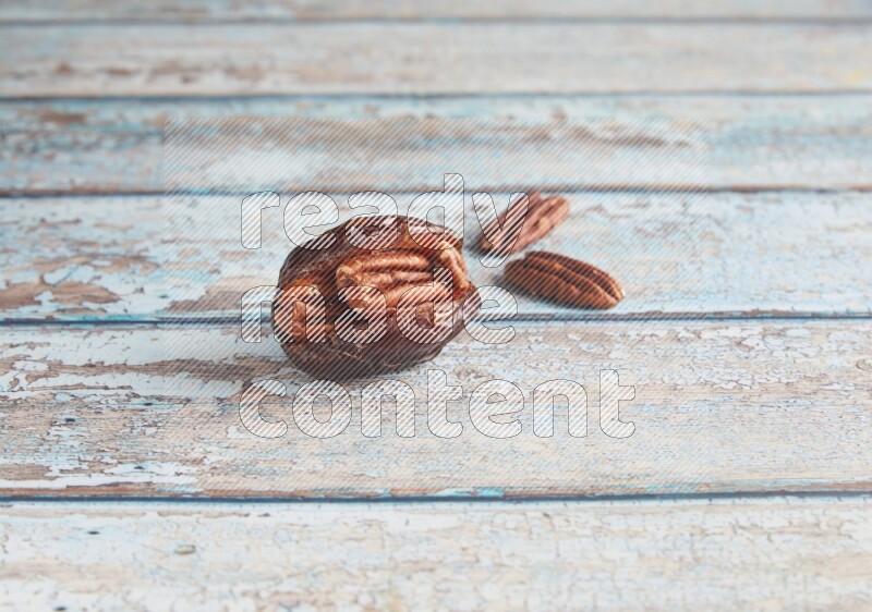 pecan stuffed madjoul date on a light blue wooden background