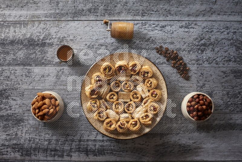 Oriental sweets in a pottery plate with nuts, coffee and honey in a dark setup