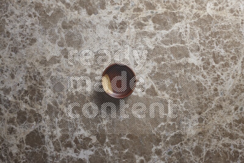 A wooden bowl on beige marble background