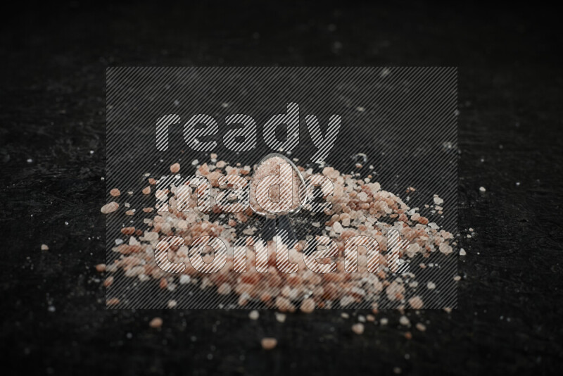 2 metal spoons filled with pink himalayan salt on black background