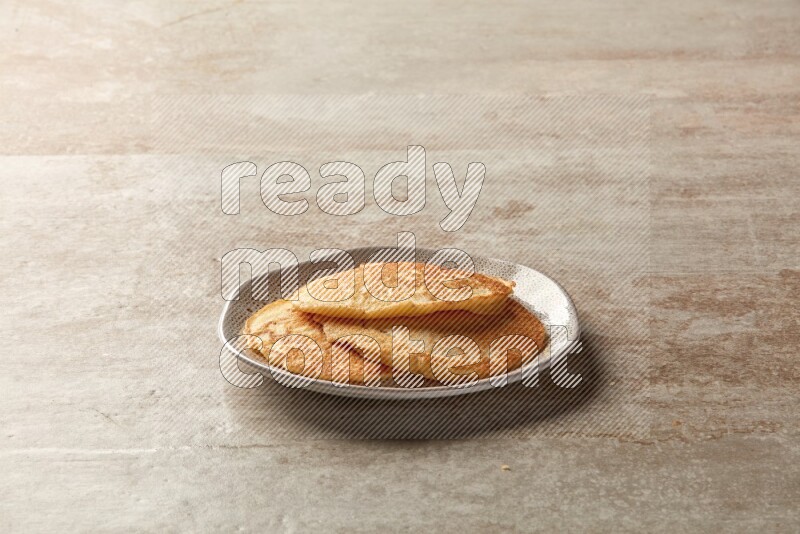 Three stacked plain pancakes in an irregular plate on beige background