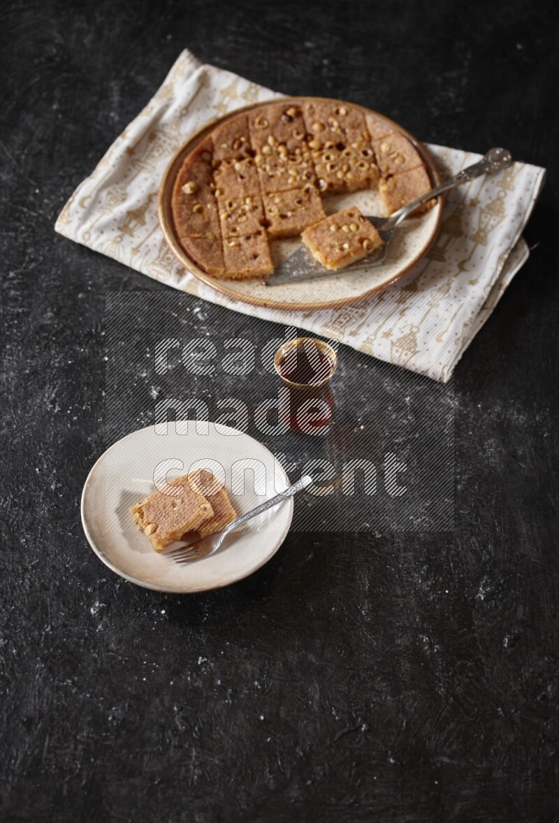 Basbousa with tea in a dark setup