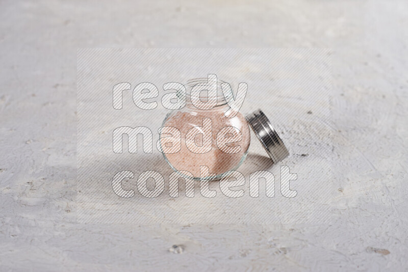 A glass jar full of fine himalayan salt on white background