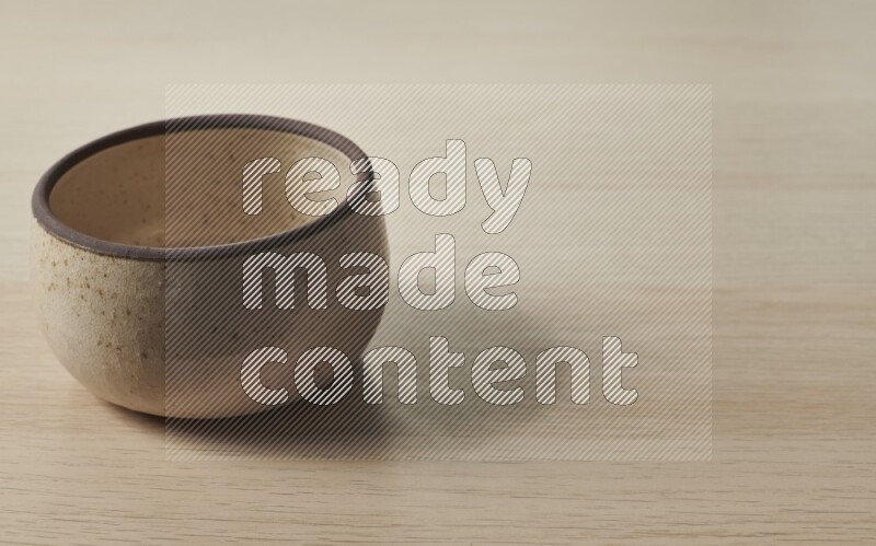 A beige pottery oven bowl on light wooden background