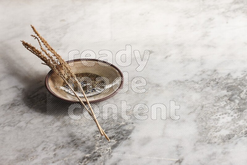 Wheat stalks on decorative pottery plate on grey marble background