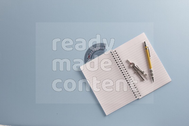 A blank open notebook with different school supplies on blue background