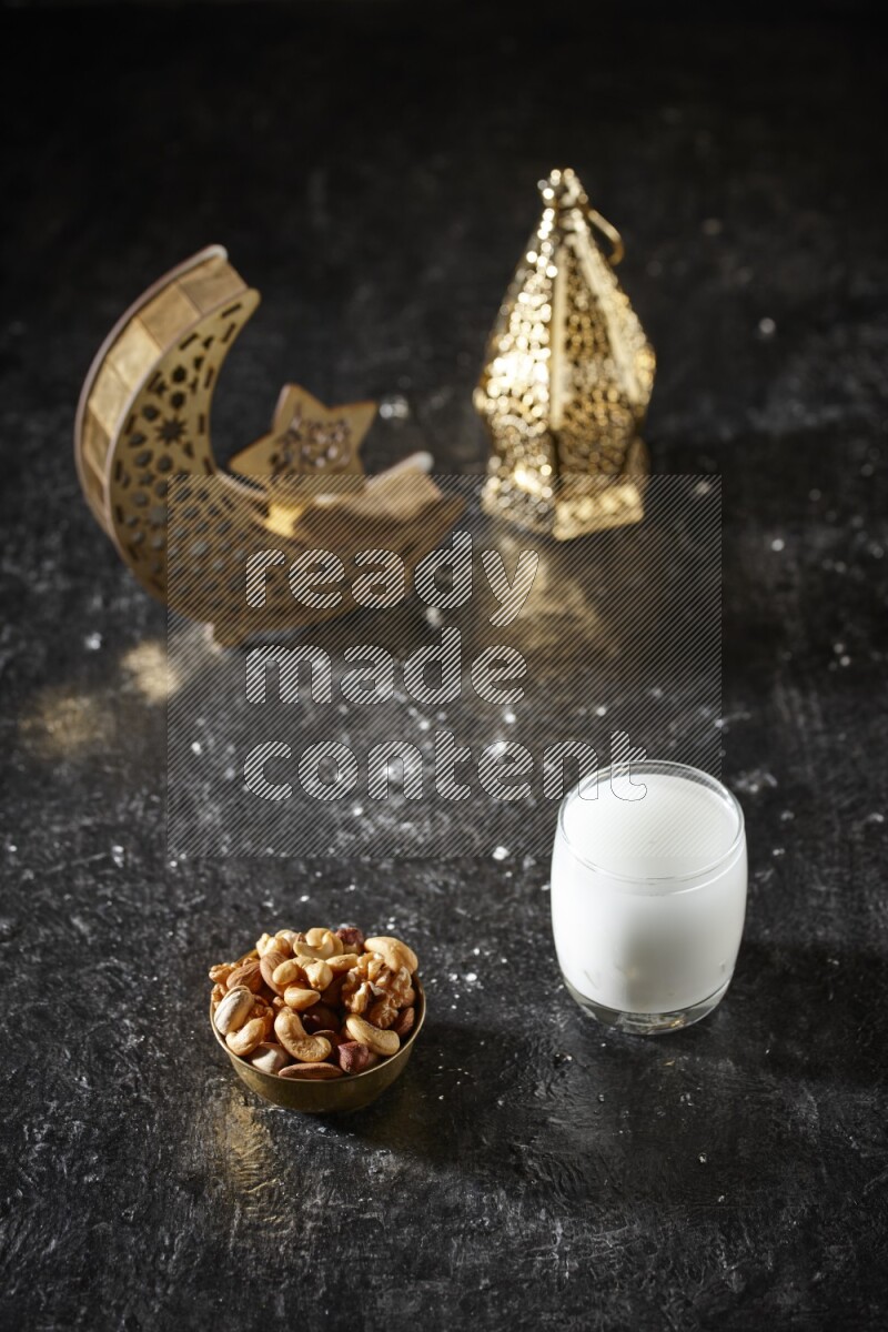 Nuts in a metal bowl with sobia beside golden lanterns in a dark setup