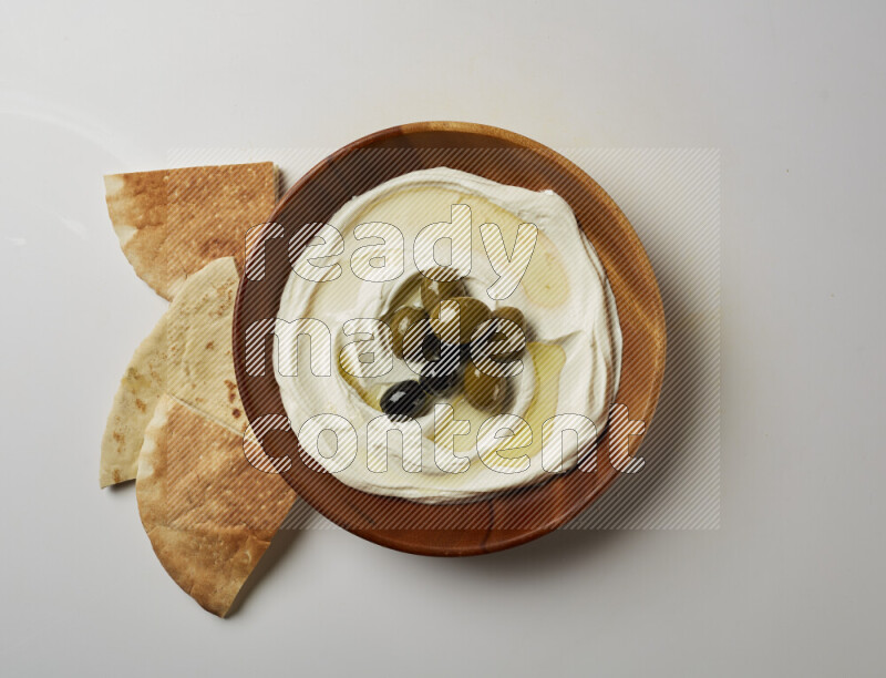 Lebnah garnished with whole olives in a wooden plate on a white background