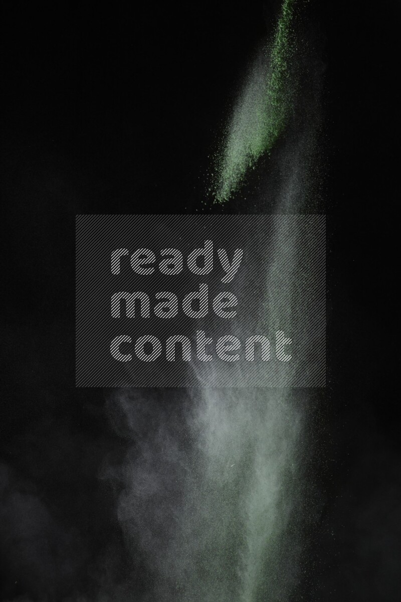 A side view of green powder explosion on black background