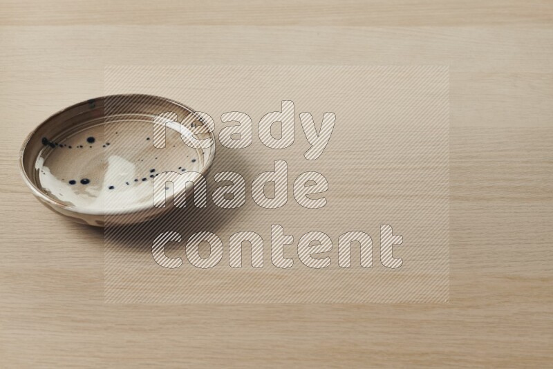 صحن فخاري متعدد الألوان على خلفية خشبية فاتحة