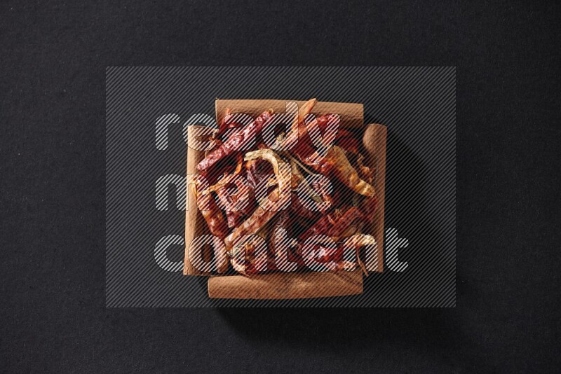 A single square of cinnamon sticks full of chilis on black flooring