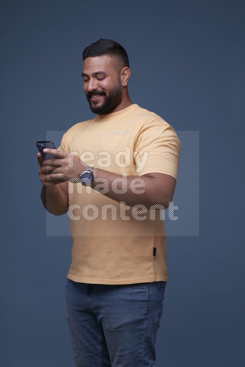 A man Texting on his phone in Blue Background wearing Orange T-shirt