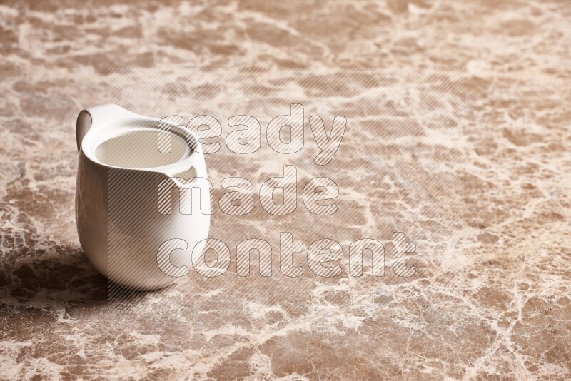 A ceramic milk jug on beige marble background