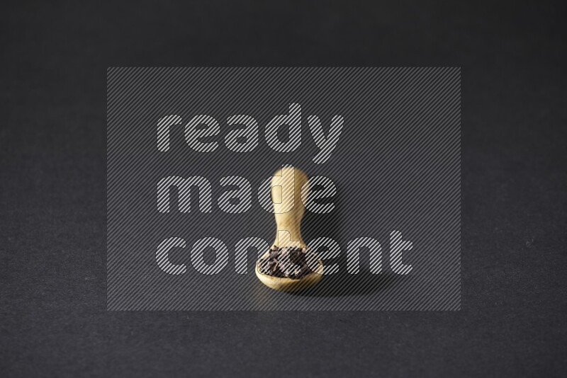 حبوب القرنفل في ملعقة خشبية علي خلفية سوداء