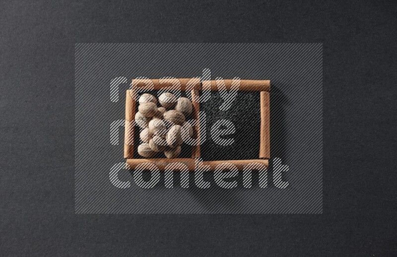 2 squares of cinnamon sticks full of black seeds and nutmeg on black flooring