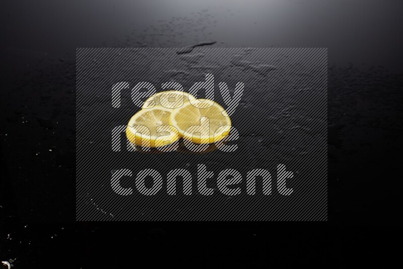 Lemon slices with water drops, and droplets on black background
