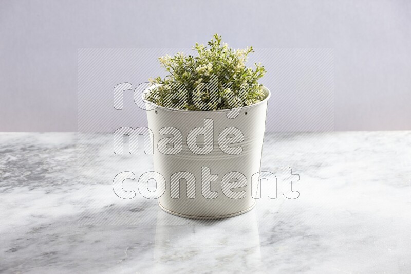 Artificial plant in white pot on grey marble background