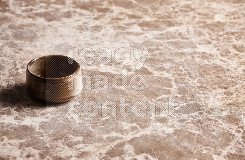 A brown pottery bowl on beige marble background