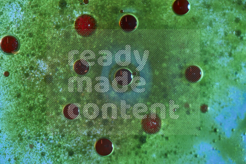 Close-ups of abstract red and green watercolor drops on oil Surface on green background