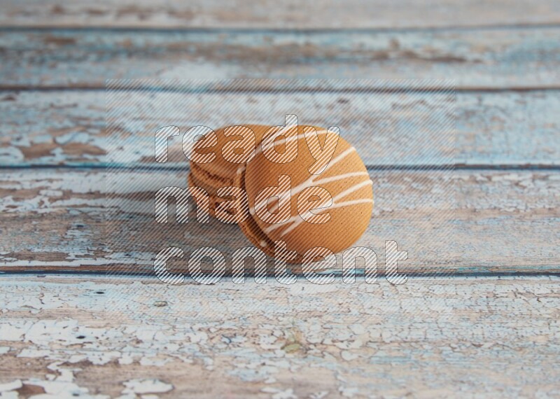 45º Shot of of two assorted Brown Irish Cream, and Brown Maple Taffy macarons  on light blue background