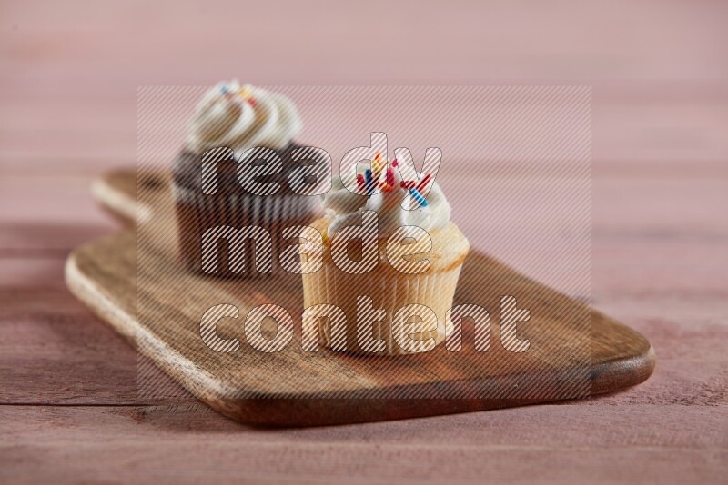 Vanilla mini cupcake topped with cream on a wooden board