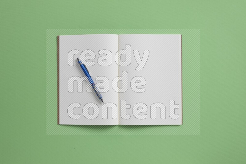 A blank open notebook with different school supplies on green background