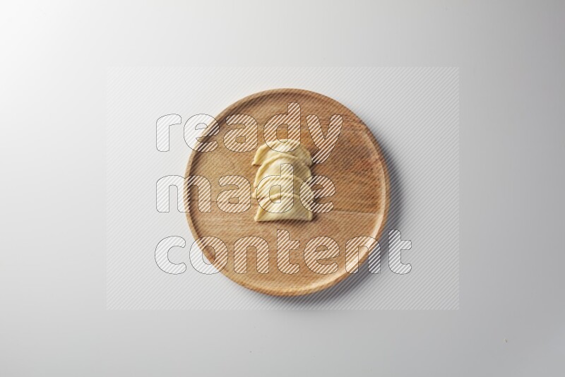 Four Sambosas on a wooden round plate on a white background
