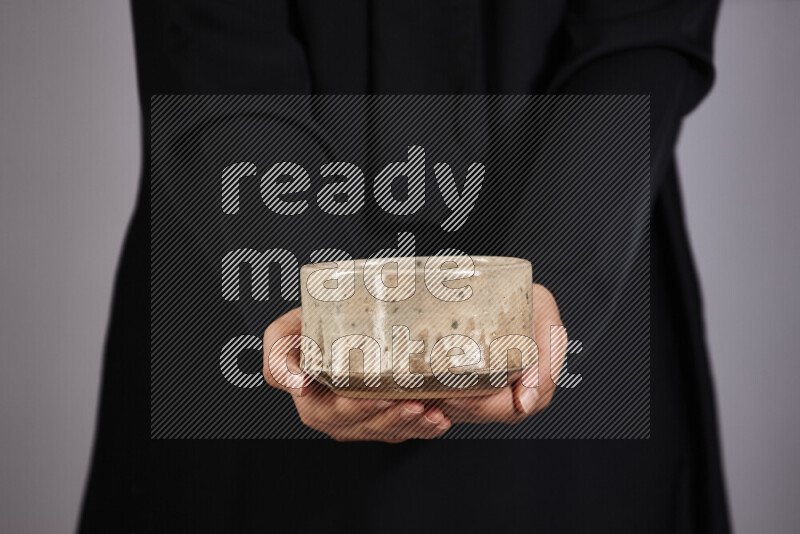 A woman in black abaya holding different pottery essentials in different positions
