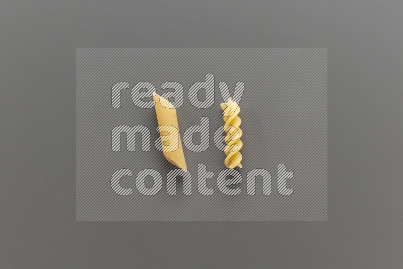 Penne pasta with other types of pasta on grey background