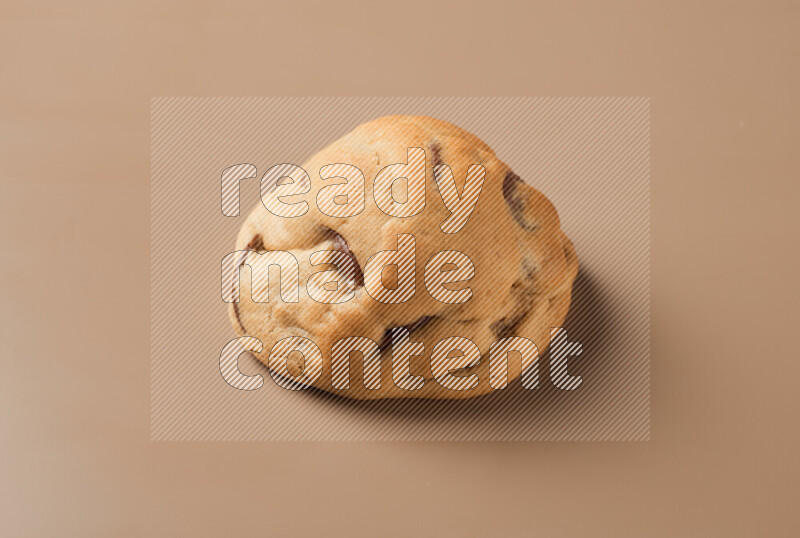 a whole chocolate chip cookie on a brown background