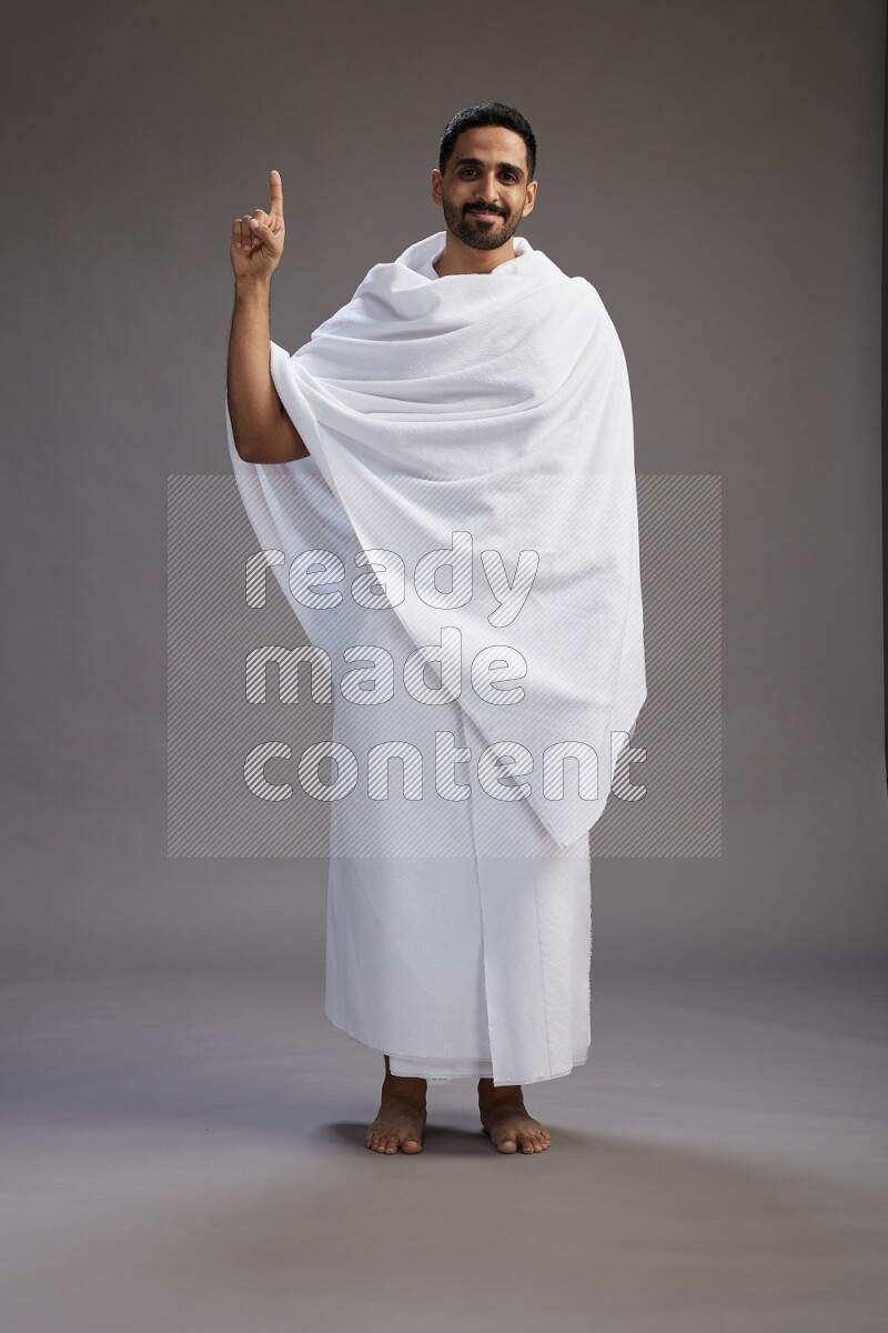 A man wearing Ehram Standing Interacting with the camera on gray background