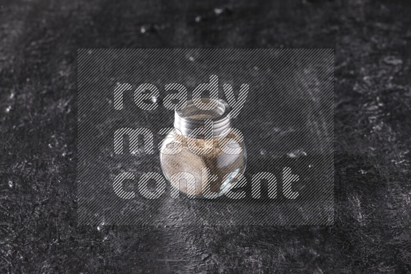 بودرة الفلفل الأسود في وعاء زجاجي علي خلفية سوداء