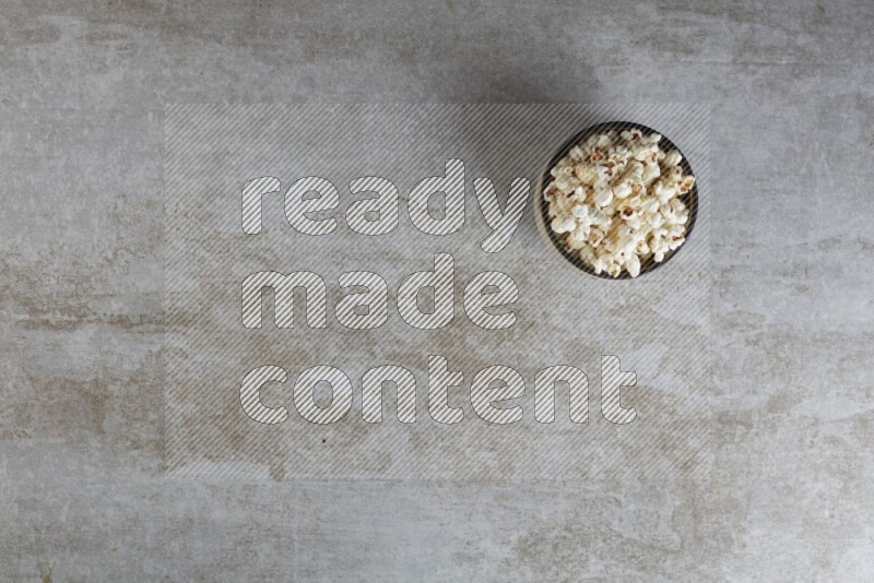 popcorn in multi-colored pottery bowl on a grey textured countertop