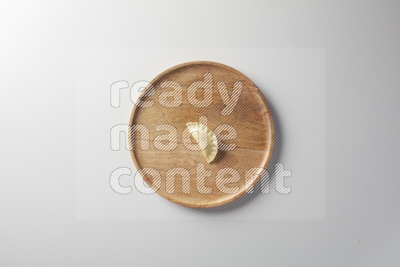 A single Sambosa on a wooden round plate on a white background