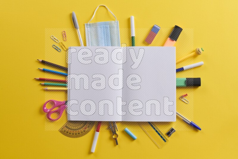 An open notebook with different school supplies on yellow background