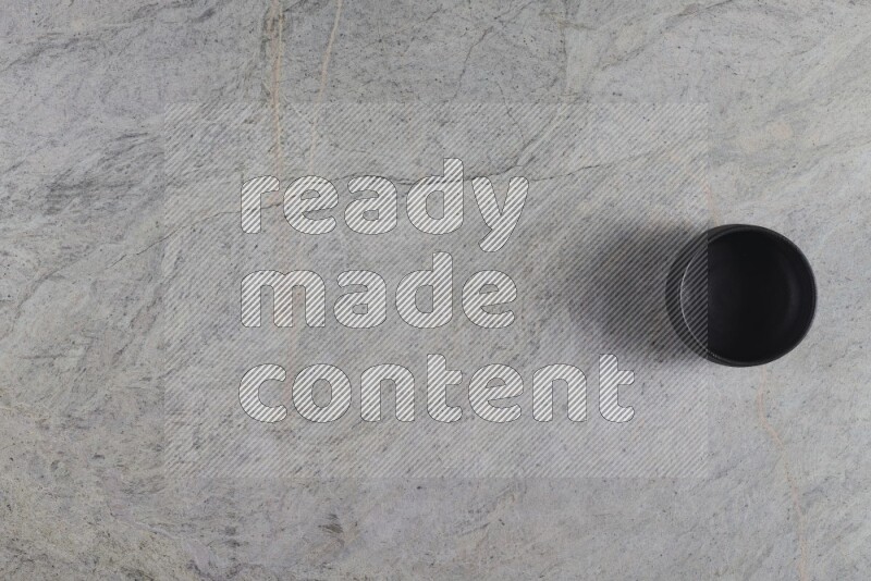 A black pottery bowl on grey marble background