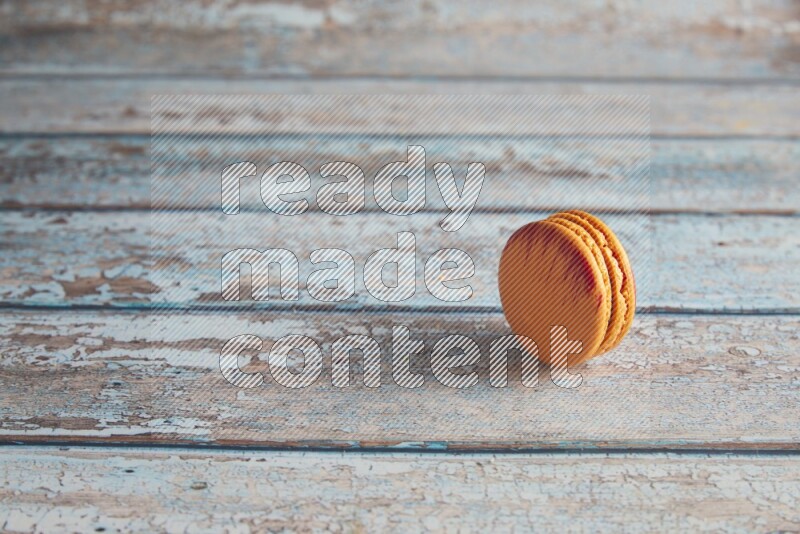 45º Shot of Orange Exotic macaron on light blue wooden background