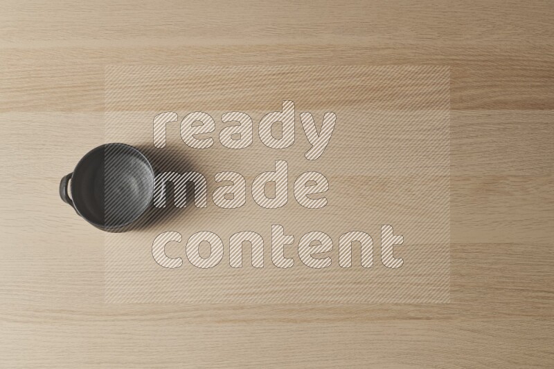 A black pottery bowl on light wooden background