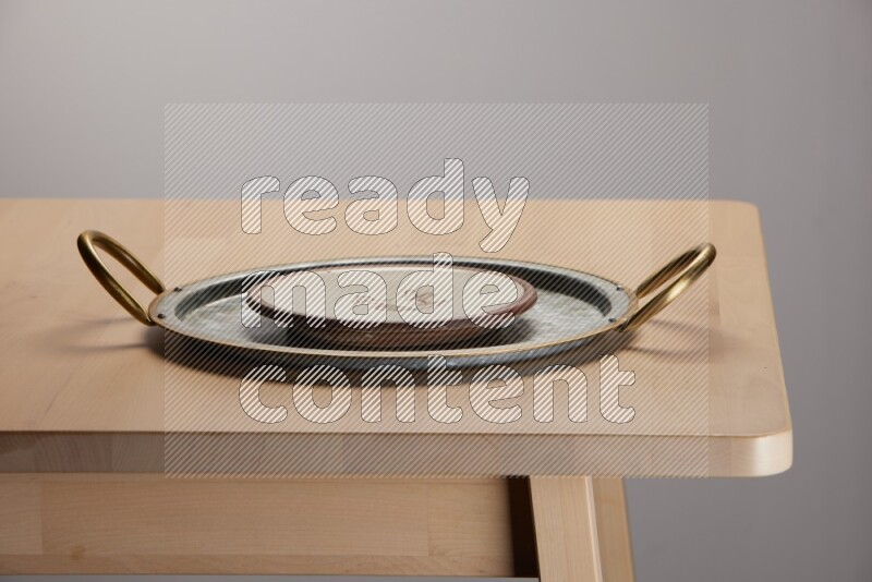 multicolored plate placed on a rounded stainless steel tray with golden handels on the edge of wooden table