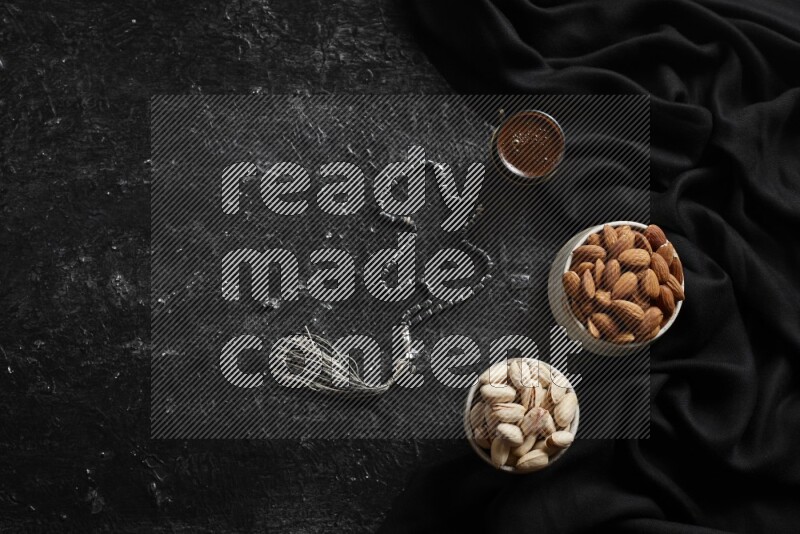 Nuts in pottery bowls with coffee in a dark setup