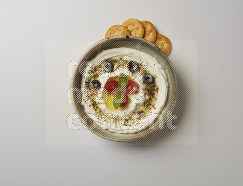 Lebnah garnished with cherry tomato, mint, olives & pine nuts in a grey pottery plate on a white background