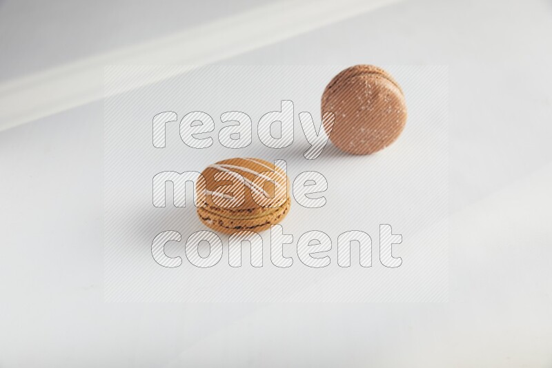 45º Shot of of two assorted Brown Irish Cream, and Brown Hazelnuts macarons on white background
